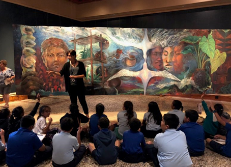 A presenter on a stage talking to young students