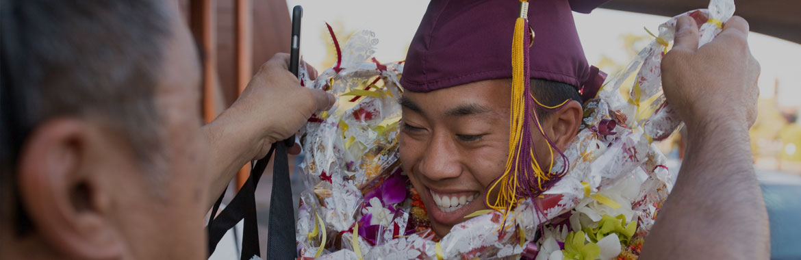 A man putting a Hawaiian Lei on an graduating ASU student.
