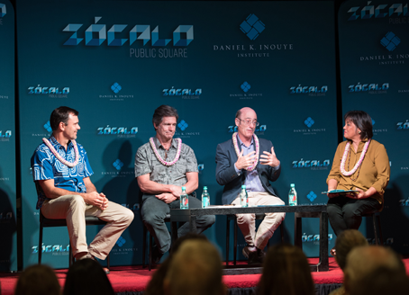 Four people on a stage during a presentation