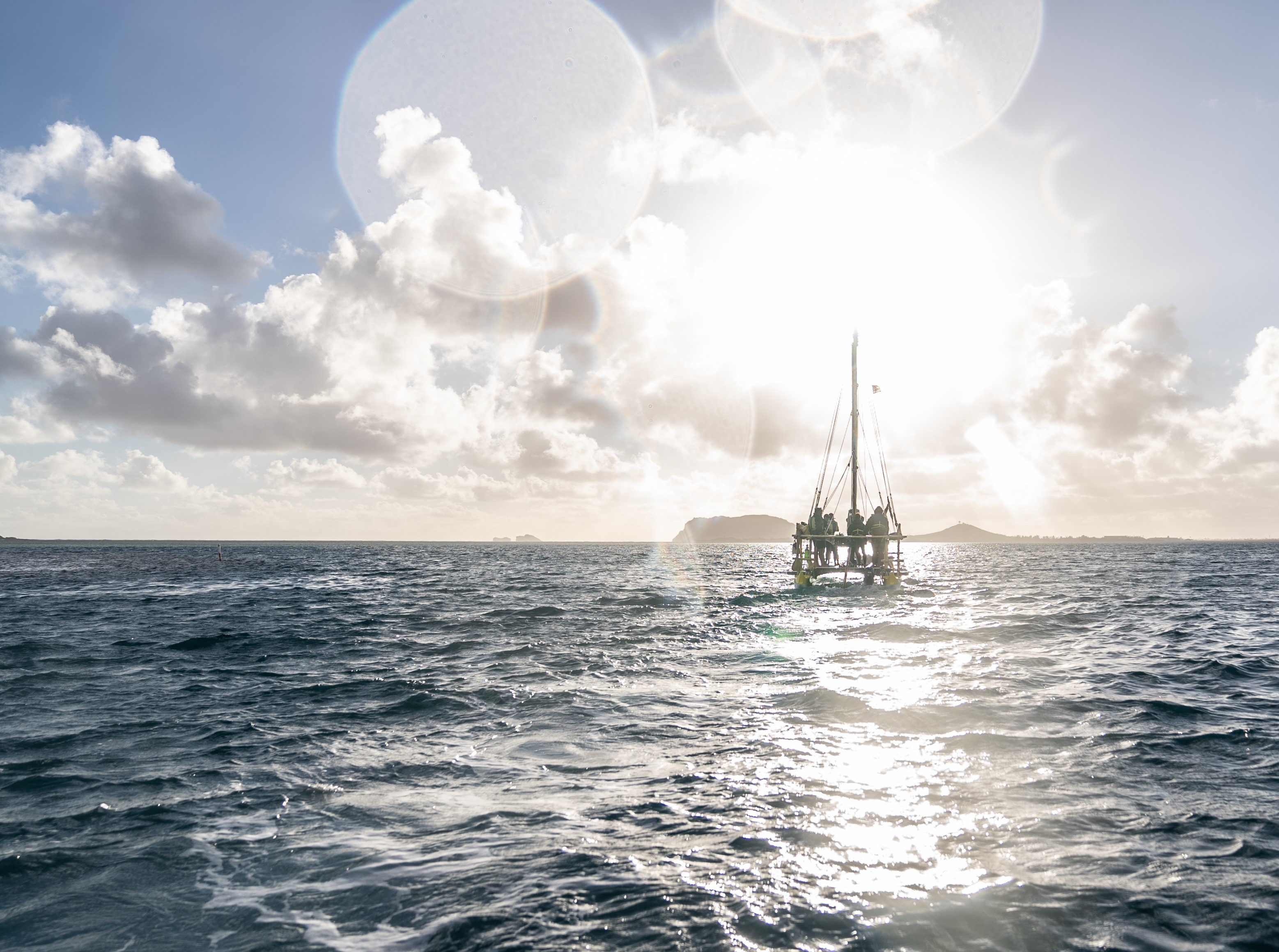 Hawaiian voyaging canoe Hokulea sailing into the sunset off the coast of Hawaiʻi